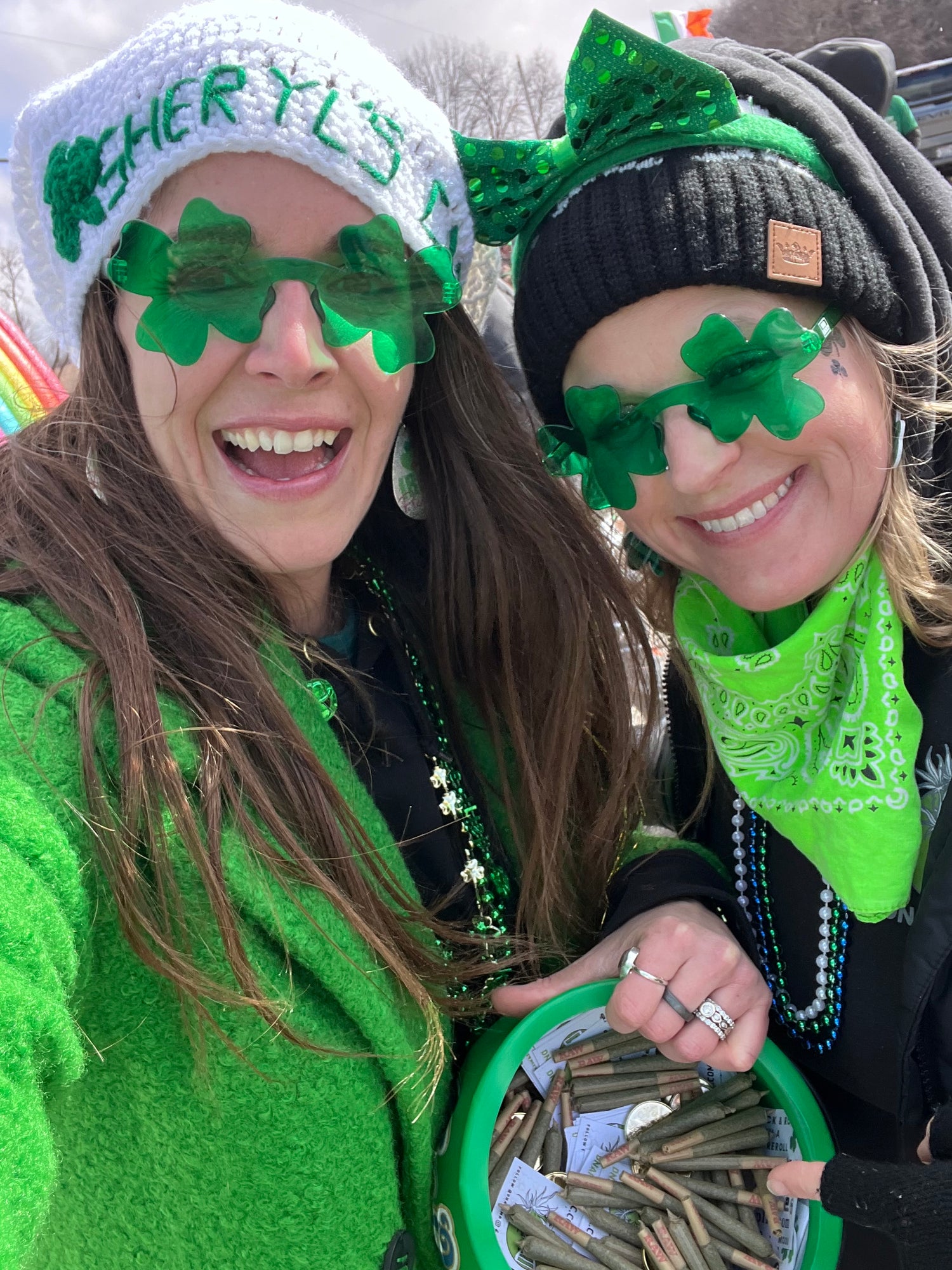 Two people wearing green hats with shamrock designs, smiling and posing together.